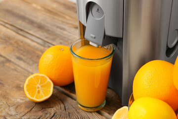 New modern juicer and glass of fresh juice with fruits on wooden table, closeup