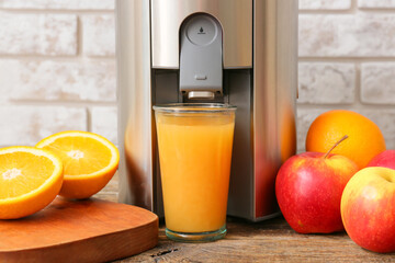 New modern juicer and glass of fresh juice with fruits on wooden table, closeup