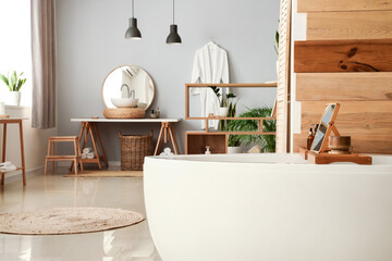 Interior of modern bathroom with white bathtub, sink and houseplants