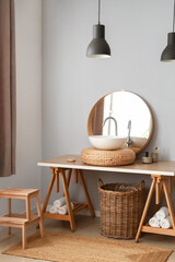 Table with sink, mirror and wicker basket near light wall