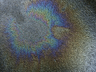 colorful stain of gasoline on wet asphalt road texture