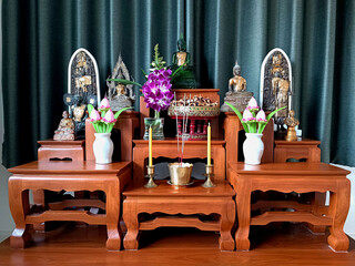 Buddha statue on altar table Enshrined with flowers on green background Bangkok Thailand.