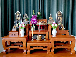 Buddha statue on altar table Enshrined with flowers on green background Bangkok Thailand.