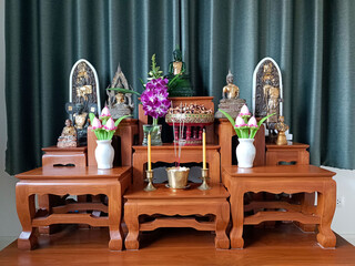 Buddha statue on altar table Enshrined with flowers on green background Bangkok Thailand.