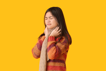 Ill Asian girl with sore throat on color background