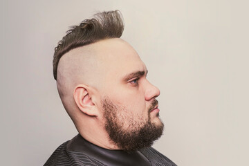 trendy man portrait. Punk styled man with Mohawk hairstyle on gray background
