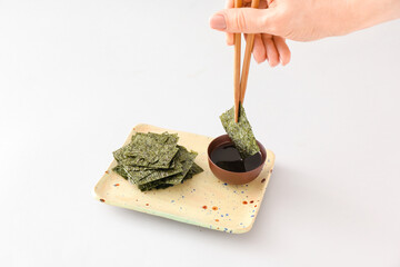 Woman eating tasty seaweed sheets on light background © Pixel-Shot
