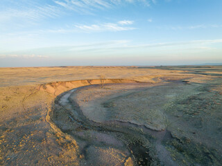 early spring on Colorado prairie - aerial view of grassland with a meandering dry stream, a lonely...