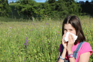 young girl blows her nose with handkerchief due to grass allergy