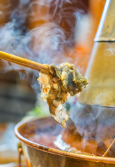 Chopsticks pick up various ingredients in the hot pot