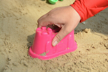 Someone catch a pink plastic kid toy castle shape for build sand castle.