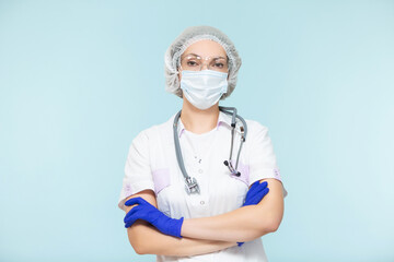 Doctor or nurse woman in a personal protective suit with a stethoscope, on a blue background. In a mask, gloves, goggles and a hat. Copy paste. healthcare concept.