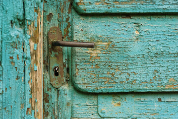 Aged door handle on wooden door with cracked paint