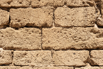 Texture of uneven stone brick wall in sunlight