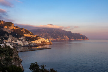 Scenic view during sunset at the coastal village of Amalfi at the Mediterranean Sea in Campania, Italy, Europe. Warm sunlight is touching the waterfront houses. Golden hour at the Amalfi Coast. Awe - obrazy, fototapety, plakaty