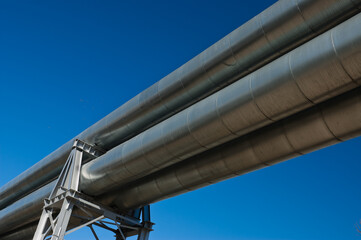 pipeline and power line pylon, in the photo, pipeline close-up, power line pylon and blue sky in the background