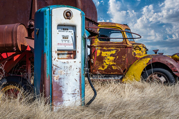 Antique gas pump in the foreground and vintage truck in the background - obrazy, fototapety, plakaty