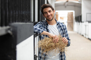 happy horse farmer holding hay in stable