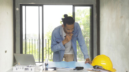 An Asian designer, worker man working on construction site on table with computer laptop notebook....