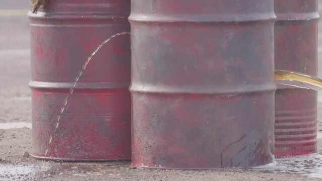 Bullet makes a hole on a red metal barrel full of water