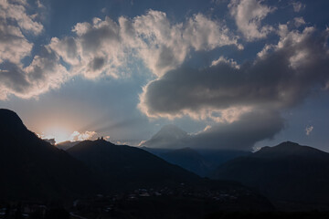 Fototapeta premium Distant view on Gergeti Trinity Church in Stepansminda, Georgia. The church is located the Greater Caucasian Mountain Range.Clouds are covering the snow-capped Mount Kazbegi in the back.Sunrise,sunset