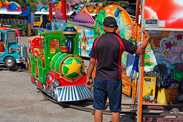 Umea, Norrland Sweden - June 29, 2021: elderly man taking care of ride at amusement park for children