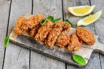 
 Crispy  deep Fried   Chicken strips and wedges potato. Breaded  with cornflakes chicken  Breast Fillets  with chilly peppers and fresh   basil on wooden rustic background