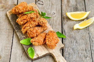 
 Crispy  deep Fried   Chicken strips and wedges potato. Breaded  with cornflakes chicken  Breast Fillets  with chilly peppers and fresh   basil on wooden rustic background