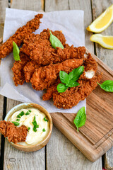 
 Crispy  deep Fried   Chicken strips and wedges potato. Breaded  with cornflakes chicken  Breast Fillets  with chilly peppers and fresh   basil on wooden rustic background