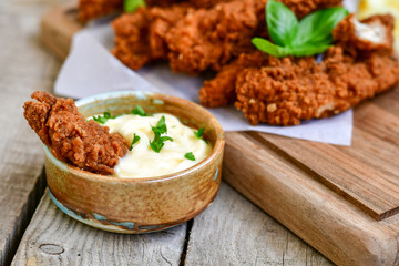 
 Crispy  deep Fried   Chicken strips and wedges potato. Breaded  with cornflakes chicken  Breast Fillets  with chilly peppers and fresh   basil on wooden rustic background