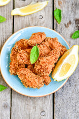 
 Crispy  deep Fried   Chicken strips and wedges potato. Breaded  with cornflakes chicken  Breast Fillets  with chilly peppers and fresh   basil on wooden rustic background