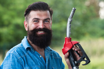 Man on petrol pump filling nozzles. Gas station. Portrait of bearded man hold fueling nozzle...