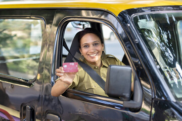 Woman taxi driver showing card sitting inside car