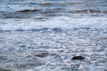 Obraz premium Pastel-gray sea. texture of a raging ocean, full frame with space for text. The concept of weather, vacation, travel. The purest clear sea water, big waves close-up. Calm natural light gray background