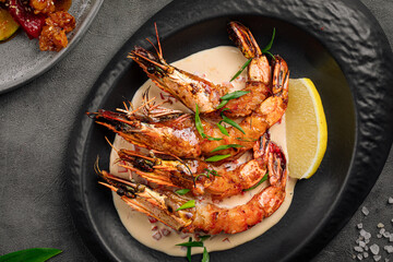 Portion of grilled tiger shrimp dish in a black plate