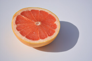 Fototapeta na wymiar Grapefruit slice on white background with a strong shadow. Pink grapefruit round slice on white. Grapefruit pink. Flat lay. Top view.