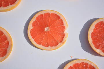 Colorful fruit pattern of fresh grapefruit slices on white background. Minimal flat lay concept.