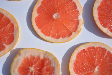 Colorful fruit pattern of fresh grapefruit slices on white background. Minimal flat lay concept.