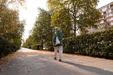 Fototapeta premium woman in hat and eco-friendly natural linen clothes walking in city in autumn fall