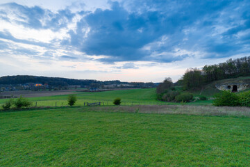 Obraz premium sunset view over the rolling hills and meadows of the most southern province of the Netherlands with a dramatic cloudscape. This valley is crossed by a small river called the Jeker