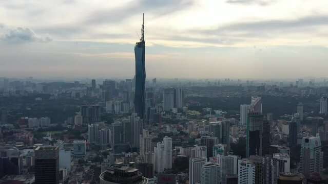 Cinematic aerial panning shot featuring Merdeka 118 in Kuala Lumpur, the second tallest building in the world, tallest building in Malaysia and Southeast Asia, dense downtown cityscape.