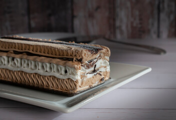 A rectangle shape coffee moka ice cream cake on a white plate with a vintage wooden wall in the background