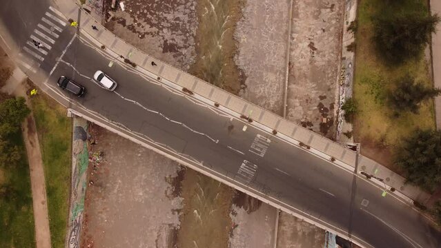 Aerial and zenithal shot of vehicular and pedestrian bridge crossing under the bridge. Camera crosses the bridge from below. cars and pedestrians crossing the mapocho river through the bridge