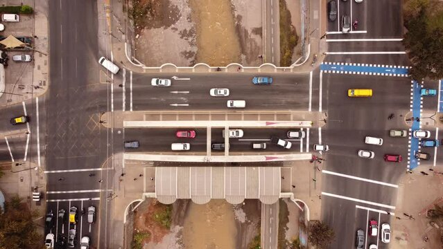 aerial drone view of a vehicular and pedestrian bridge while cars and people cross it