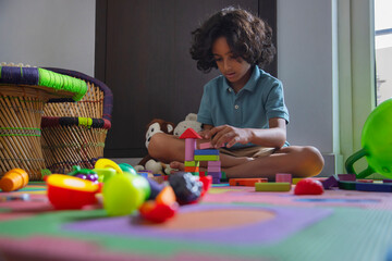 Little child playing with toy blocks in living room