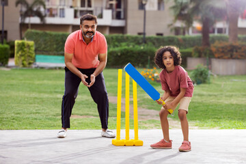 Family playing cricket in the park