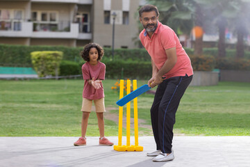 Family playing cricket in the park