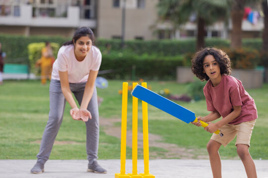 Family Playing Cricket In The Park