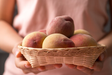 Peach fruit in basket holding by woman hand