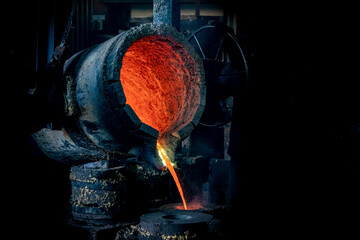 Foundry production. A ladle with molten metal. Pouring hot liquid metal into special molds. Close-up